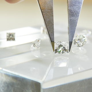 loose diamonds spread on table with jewelry tools