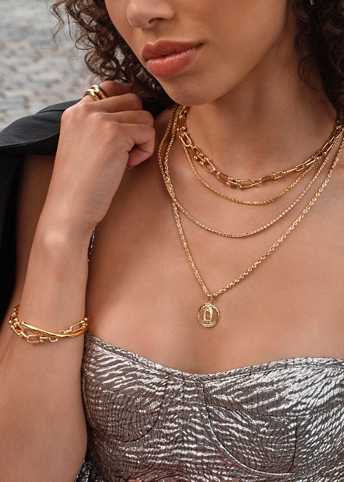 Woman wearing layered gold necklaces and rings from KAY