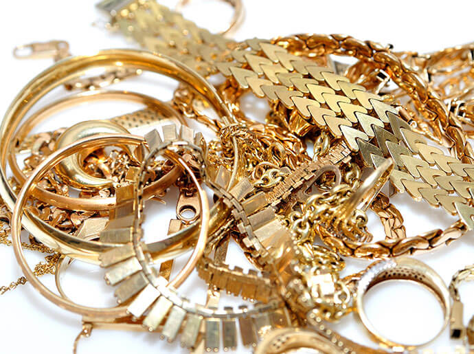A pile of gold jewelry rests on a white background.