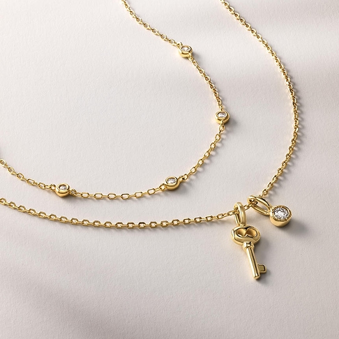 Two gold necklaces. One with diamond studs, and another with a key pendant and a diamond pendant attached from KAY.