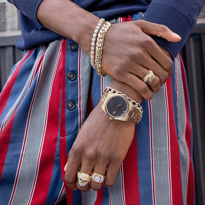 A man displying gold bracelets, rings and a watch.