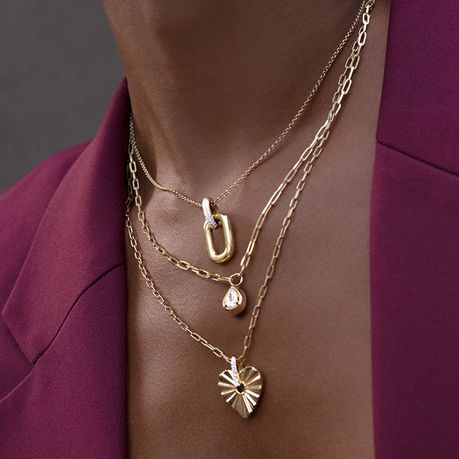 A woman showing off gold stacking necklaces.