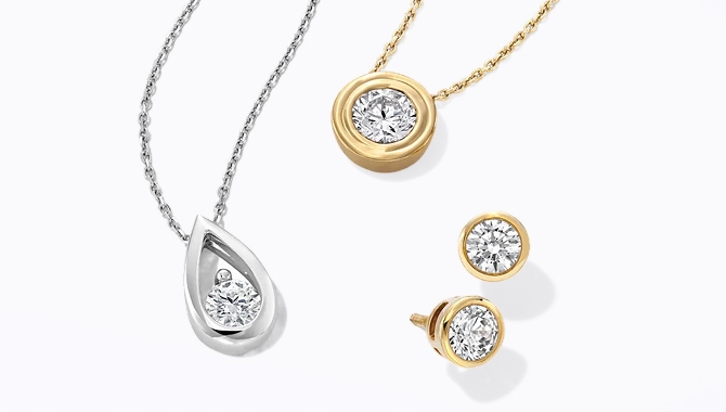 A set of one silver and one gold solitaire chains and pendant, alongside a pair of similar 