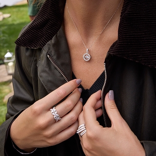  woman displaying her silver and diamond necklace and rings.