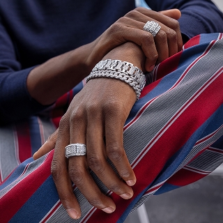 A man wearing silver chain style bracelets and diamond rings.