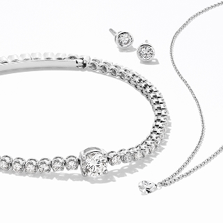A set of lab-grown diamond jewelry including a silver bracelet, earrings, and a necklace.
