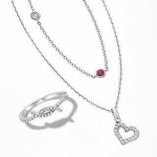 A silver ring studded with diamonds, and two silver necklaces; one with a garnet stone pendant and the other with a diamond studded heart.