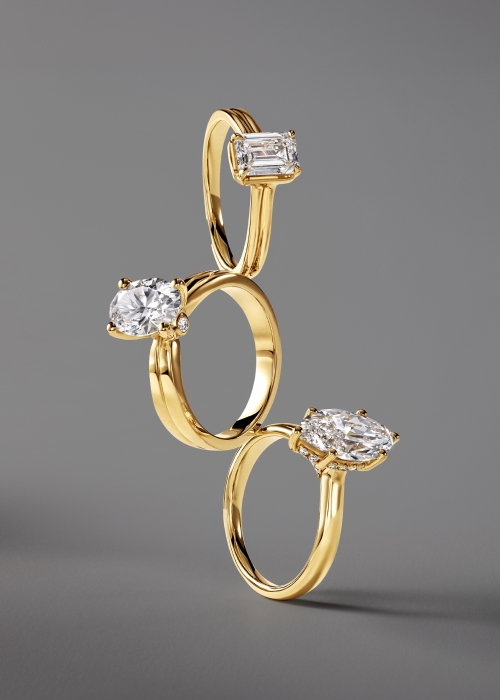 Gold emerald, oval, and marquise solitaire rings stacked on each other