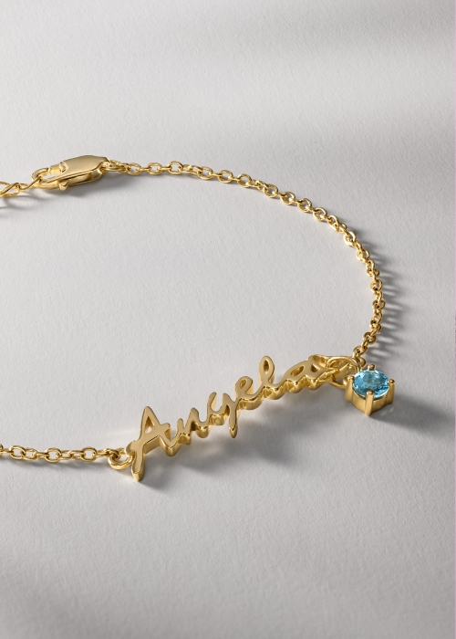 Gold chain nameplate bracelet personalized with aquamarine birthstone and the name Angela