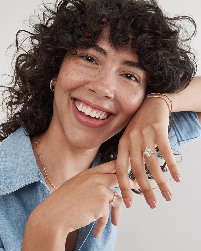 A woman wearing a matching diamond tennis bracelets and necklace, along with her Lab-Grown Diamond Engagement Ring from KAY.