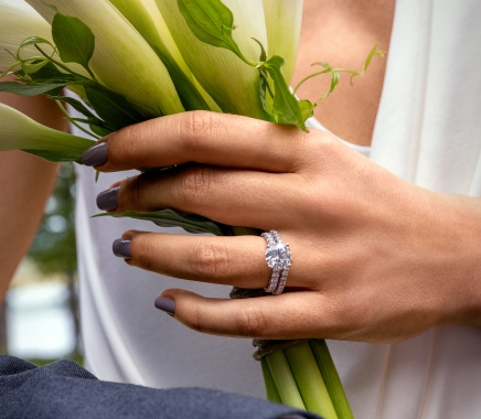 A woman holding flowers wearing a silver and diamond ring.