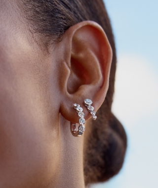 A women wearing stacking silver and diamond earrings.
