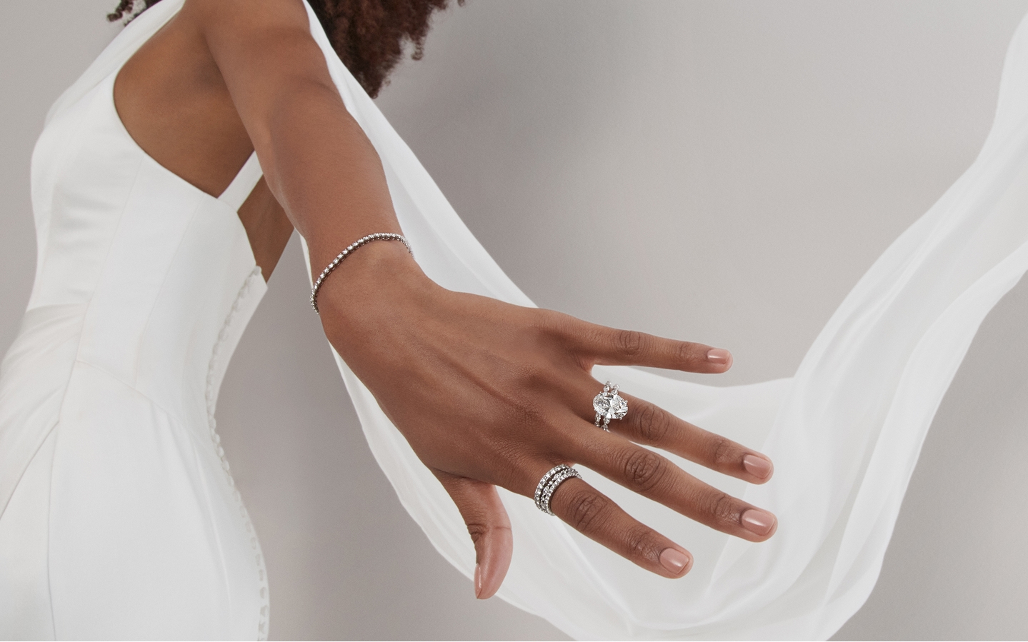 Woman in flowing wedding dress showing off diamond engagement ring