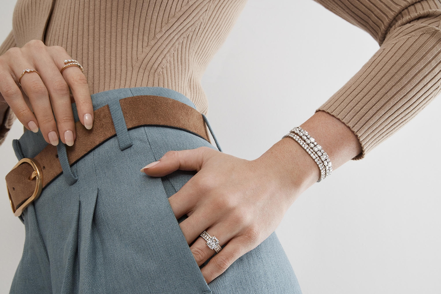 Woman with her hand in her pocket wearing lots of diamond jewelry