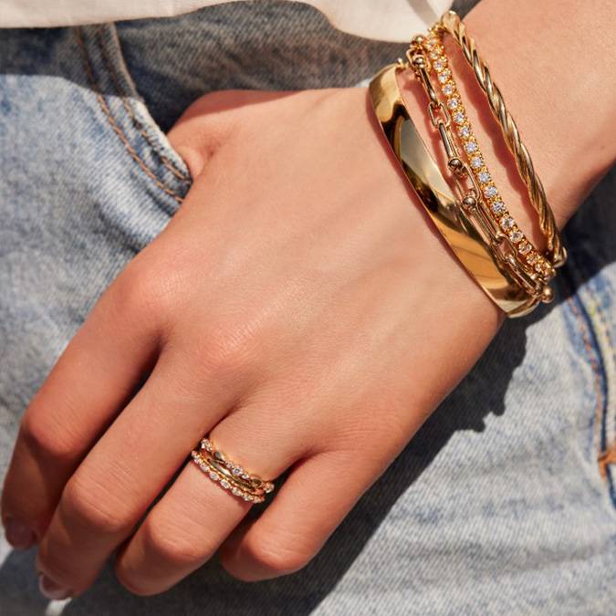 Woman's hand in pocket with a stack of layered gold bracelets