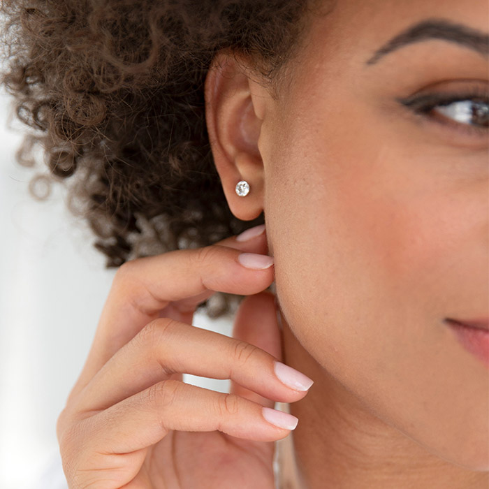 Woman wearing diamond solitaire earrings from KAY