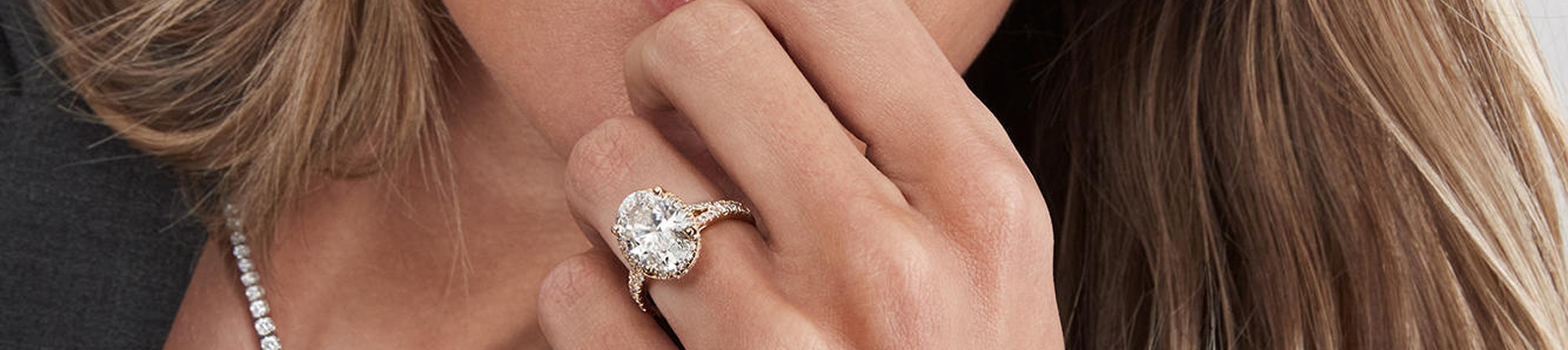 Woman wearing diamond tennis necklace and Kay Signature oval diamond ring