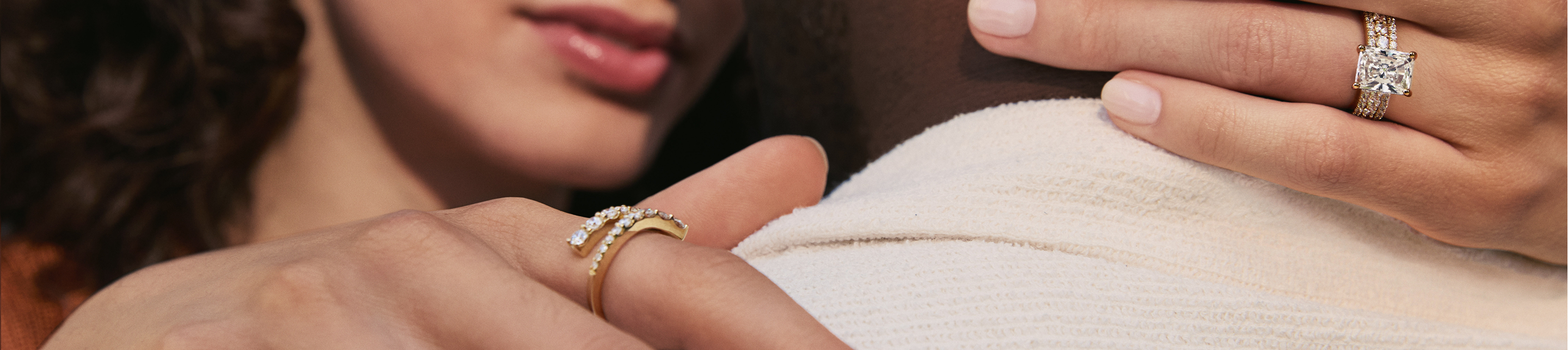 Woman wearing emerald cut diamond engagement ring and Le Vian ring resting her hands on mans neck