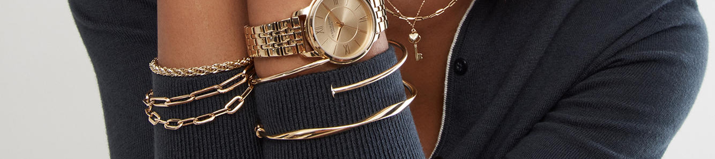 Close up of woman wearing gold bracelets, necklaces, and watch