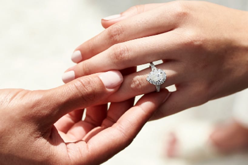 Pear diamond engagement ring on woman's hand and man holding her hand