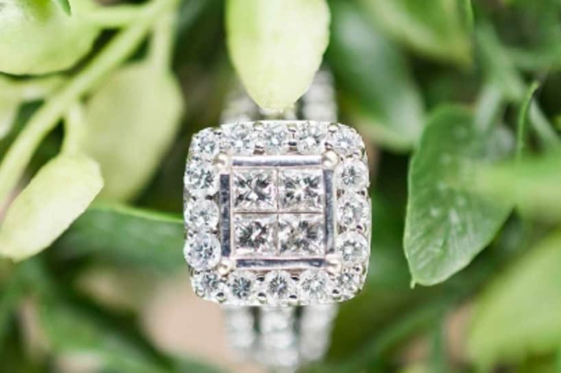 Princess cut diamond engagement ring resting on greenery