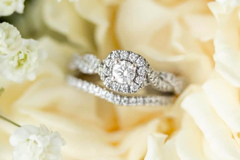 Round diamond engagement ring resting on white flowers