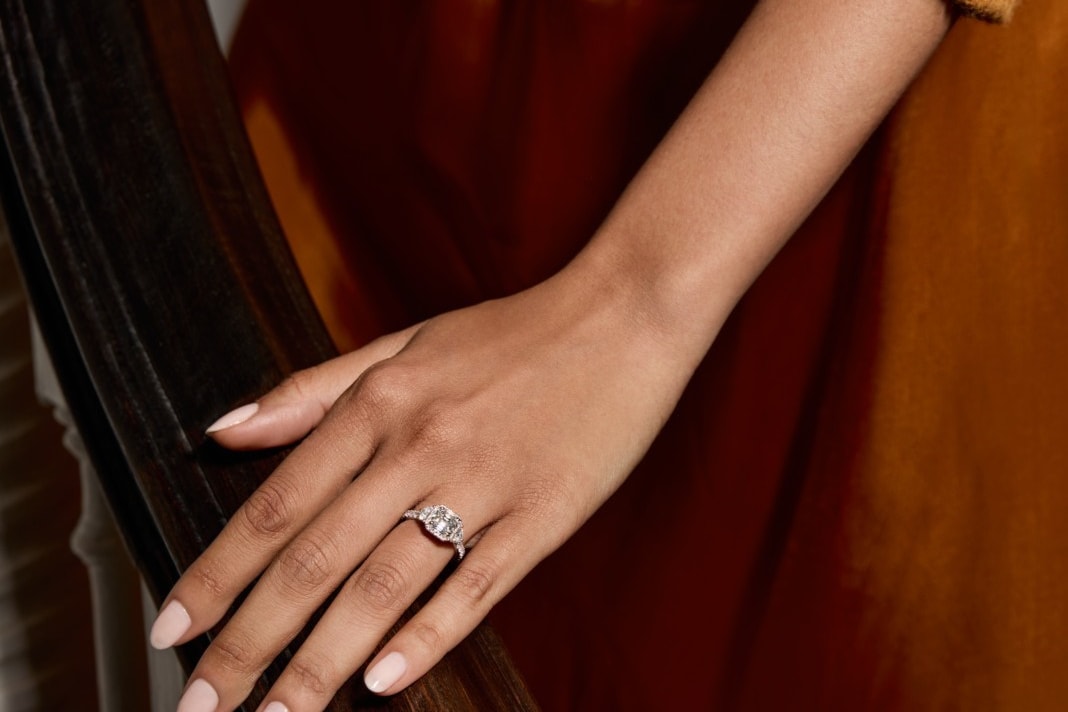 Image of hand wearing engagement ring resting on bannister