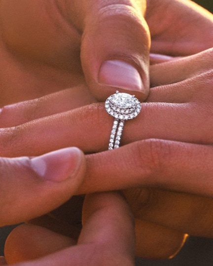 Image of hand holding hand wearing engagement ring