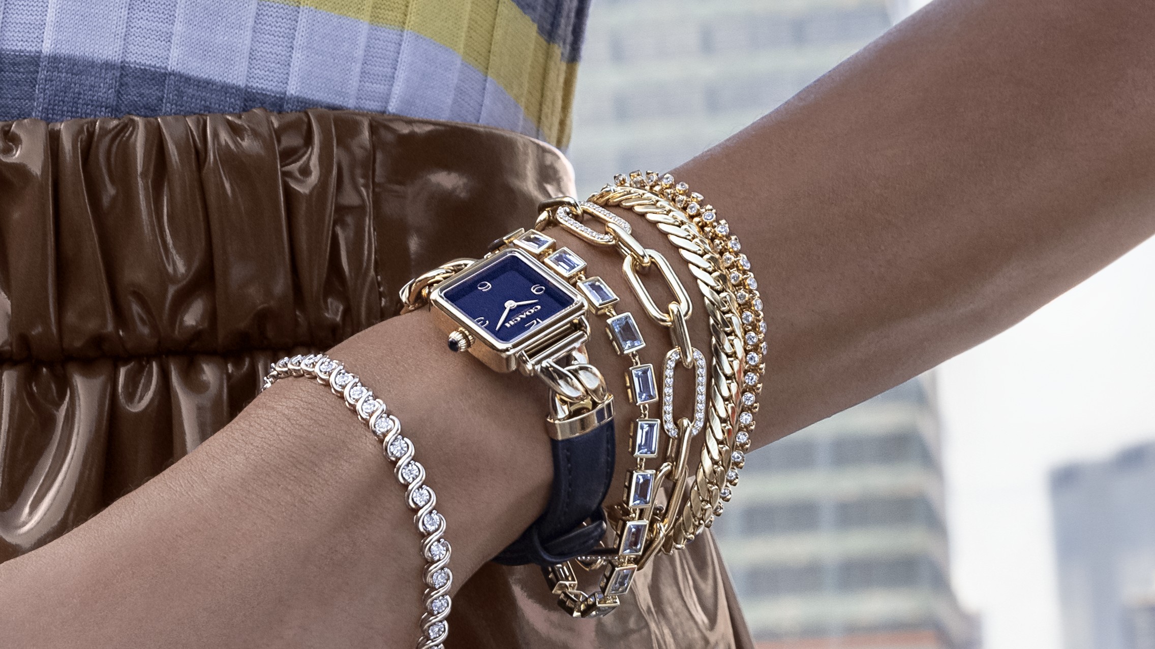 Woman wearing blue Coach watch with several bracelets