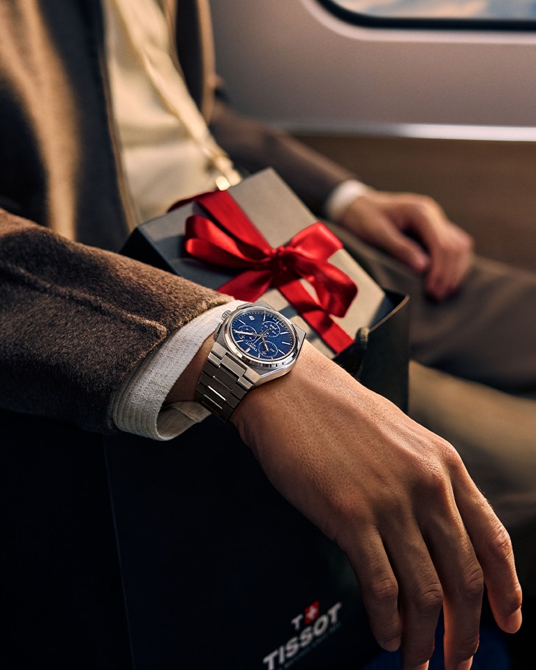 Man wearing Tissot watch sitting on plane with gift box in his lap