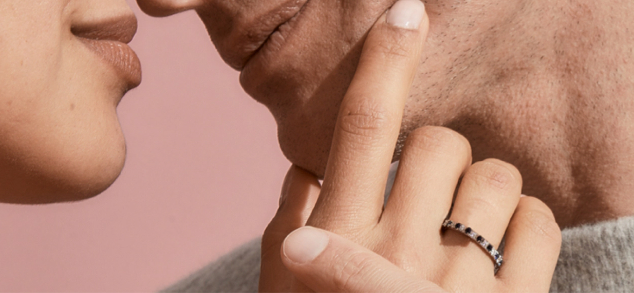 Woman caressing man's face and wearing a gemstone anniversary band