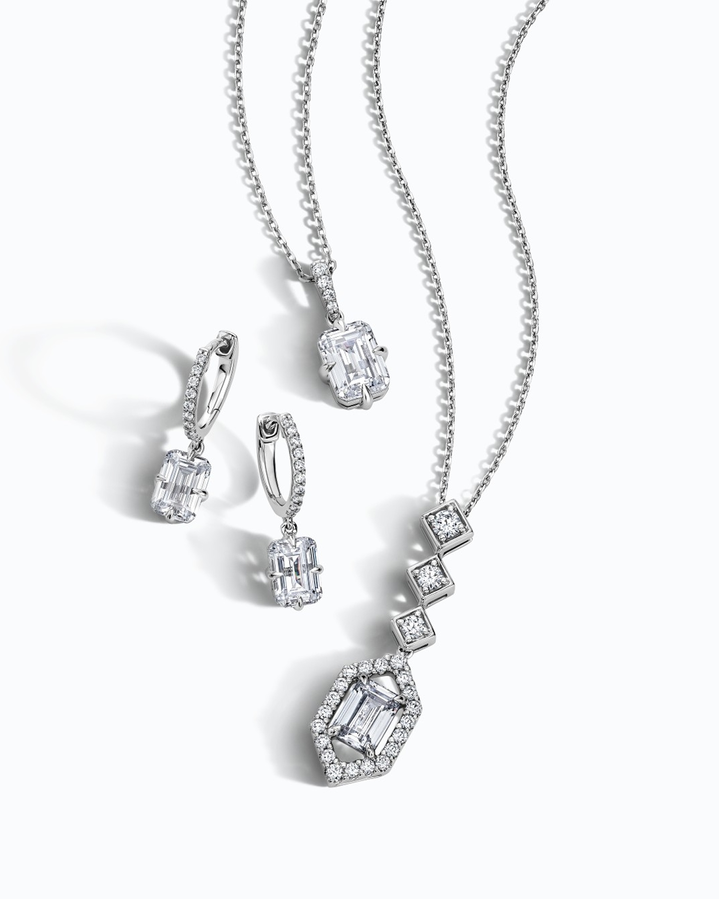 Kay Neil Lane Artistry diamond jewelry collection featuring emerald-cut diamond drop earrings, an emerald-cut diamond pendant necklace, and a geometric halo diamond necklace in white gold, showcasing exceptional brilliance and designer-inspired elegance.
