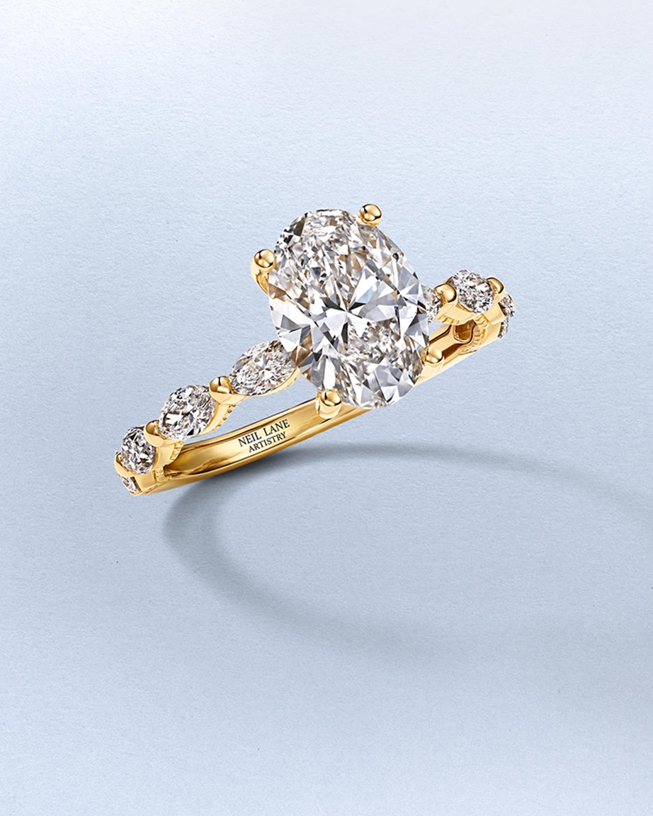 Kay Neil Lane Artistry oval-cut diamond engagement ring in yellow gold featuring a brilliant center diamond and graduated diamond-accent band, showcased against a soft neutral background.