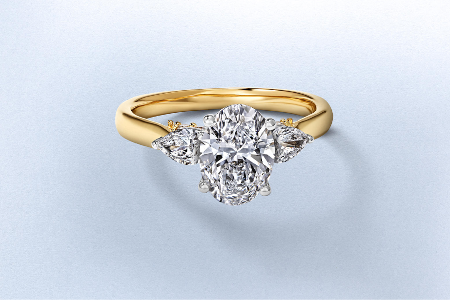 Kay oval-cut diamond engagement ring featuring a brilliant center diamond accented by pear-shaped side stones in a yellow gold setting, showcasing a timeless three-stone design with exceptional sparkle and elegant bridal style.