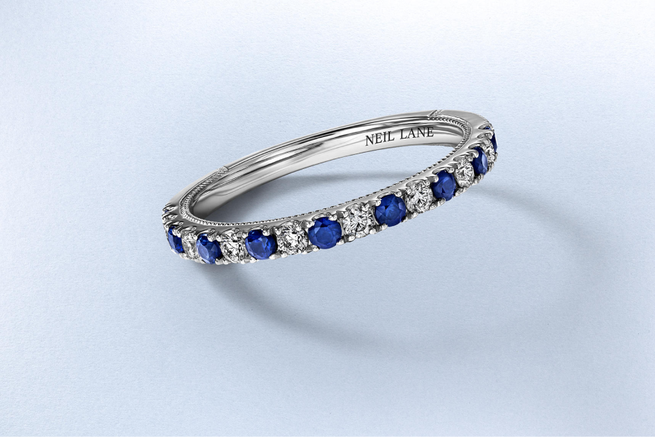 Kay Neil Lane stackable ring featuring alternating round blue sapphires and round diamonds in a white gold band with milgrain detailing, showcasing vibrant color, vintage-inspired design and elegant everyday sparkle.