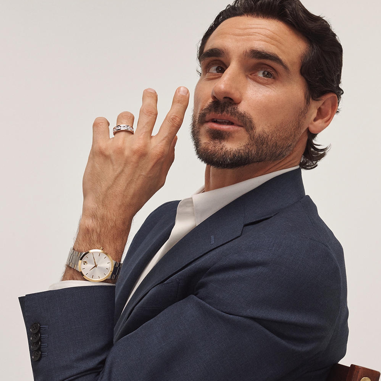 Kay Leo Diamond men's wedding band featuring channel-set round diamonds in polished white gold, showcased in a sophisticated lifestyle portrait with a classic two-tone watch